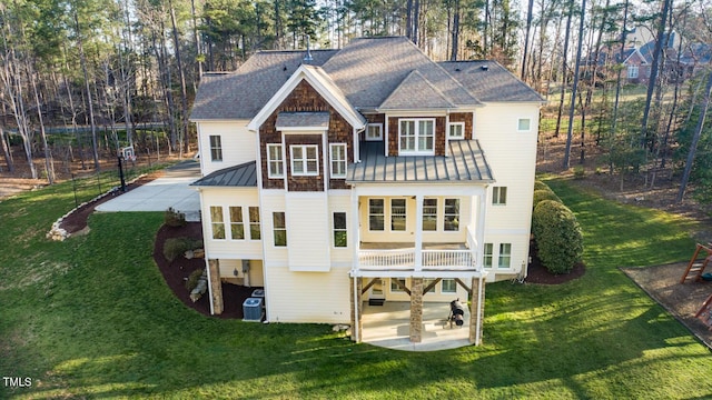 rear view of house featuring a standing seam roof, central AC unit, metal roof, a yard, and a patio