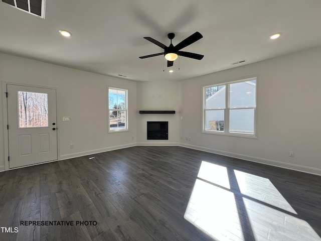 unfurnished living room with recessed lighting, visible vents, dark wood-style flooring, and a glass covered fireplace