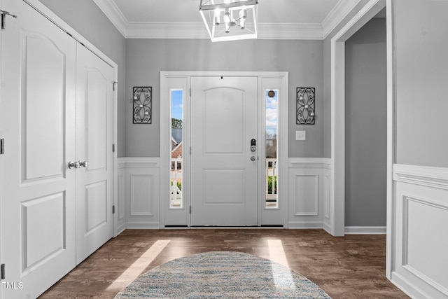 entrance foyer featuring a decorative wall, wood finished floors, and crown molding