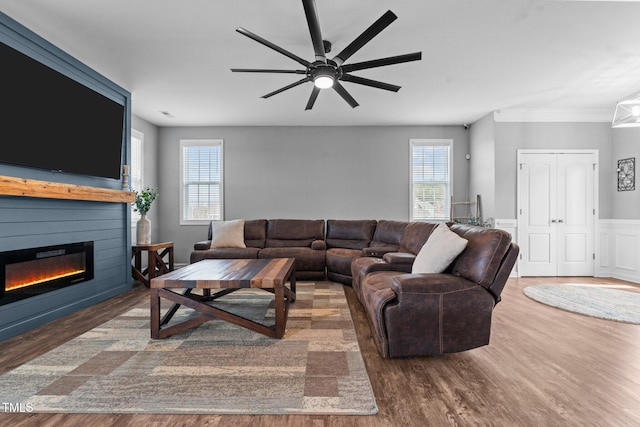 living room with a wealth of natural light, a glass covered fireplace, and wood finished floors