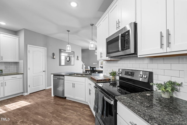 kitchen with stainless steel appliances, a peninsula, a sink, and white cabinetry