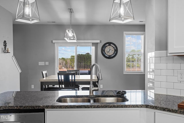 kitchen with tasteful backsplash, dark stone countertops, a sink, and a healthy amount of sunlight