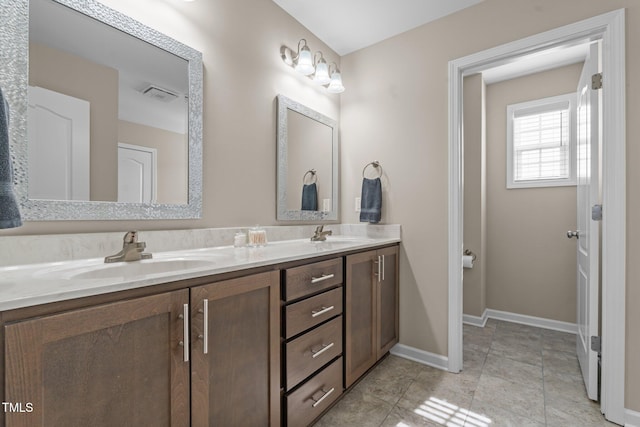 bathroom featuring double vanity, baseboards, visible vents, and a sink