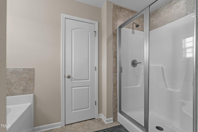 full bath featuring baseboards, a stall shower, a garden tub, and tile patterned floors