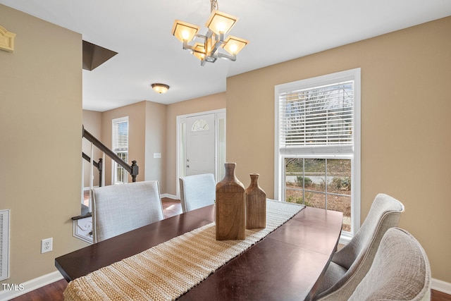 dining room with stairs, an inviting chandelier, plenty of natural light, and baseboards