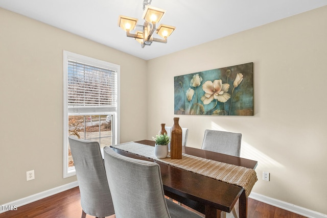 dining room with dark wood finished floors, a notable chandelier, and baseboards