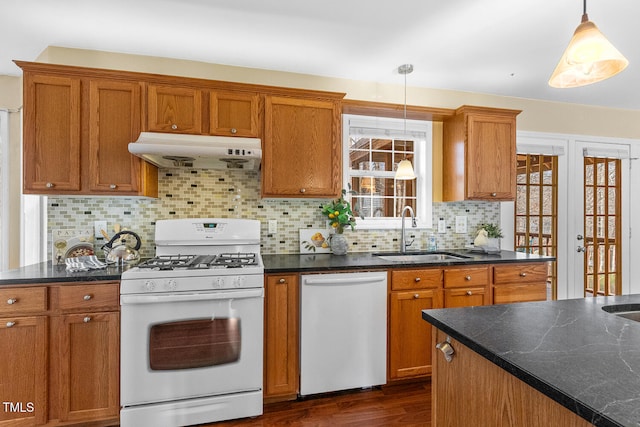 kitchen with white gas range, a sink, under cabinet range hood, dishwasher, and brown cabinets