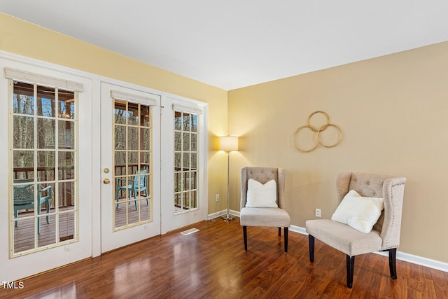 living area featuring visible vents, baseboards, and wood finished floors