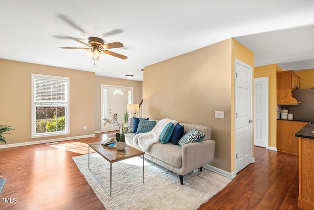 living area with dark wood-style floors, visible vents, a ceiling fan, and baseboards