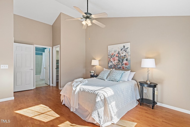 bedroom with baseboards, light wood-style floors, ensuite bathroom, and high vaulted ceiling