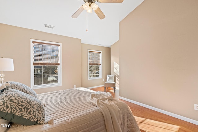 bedroom featuring visible vents, a ceiling fan, baseboards, and wood finished floors