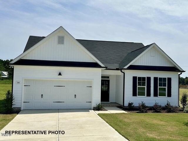 view of front of house with an attached garage, driveway, a front lawn, and board and batten siding