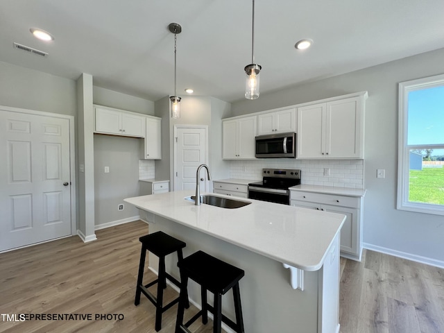 kitchen with stainless steel appliances, a sink, visible vents, and decorative backsplash