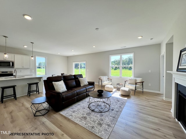 living area featuring recessed lighting, light wood finished floors, baseboards, and a fireplace
