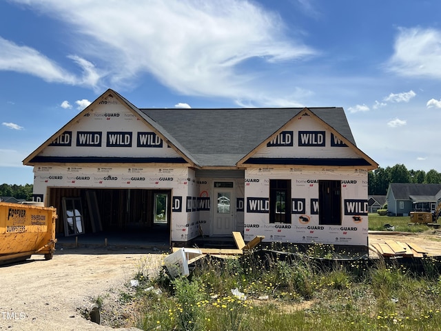 unfinished property with a garage, driveway, and roof with shingles