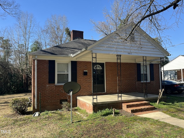 bungalow with brick siding, a porch, and a chimney