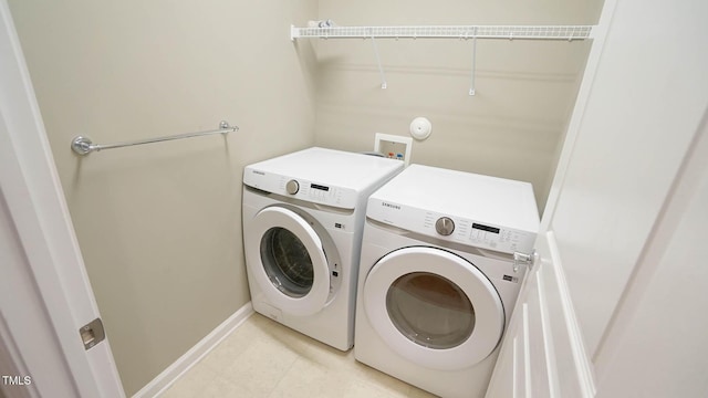 washroom featuring laundry area, light tile patterned flooring, separate washer and dryer, and baseboards