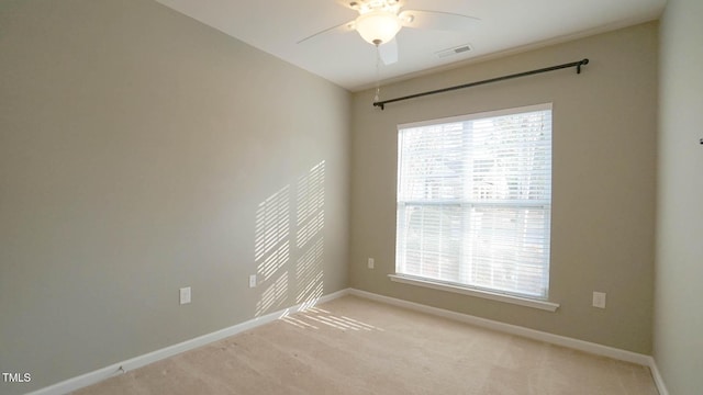 unfurnished room featuring a wealth of natural light, visible vents, ceiling fan, and baseboards