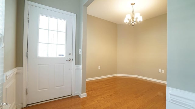 entryway featuring light wood-type flooring, baseboards, and a chandelier