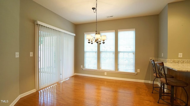 dining room featuring visible vents, baseboards, a notable chandelier, and wood finished floors