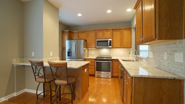 kitchen with brown cabinets, a peninsula, stainless steel appliances, and a sink