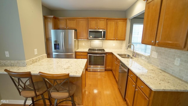 kitchen with a sink, a breakfast bar, brown cabinets, and stainless steel appliances