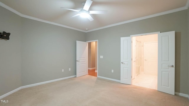 unfurnished bedroom featuring carpet, baseboards, ceiling fan, ensuite bathroom, and crown molding