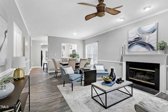 living room with crown molding, wood finished floors, and a glass covered fireplace