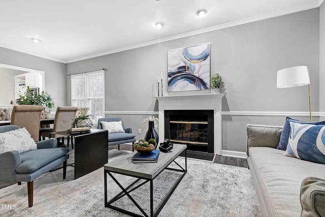 living area featuring a fireplace with flush hearth, ornamental molding, baseboards, and wood finished floors