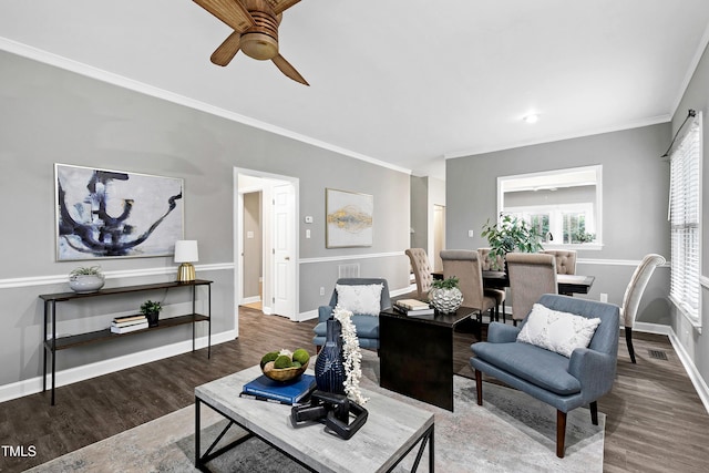 living area featuring baseboards, crown molding, visible vents, and wood finished floors