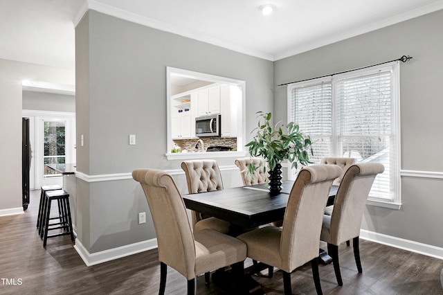 dining room featuring dark wood-style flooring, crown molding, and baseboards