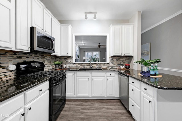 kitchen with tasteful backsplash, appliances with stainless steel finishes, white cabinets, a sink, and wood finished floors