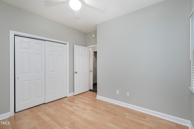 unfurnished bedroom featuring a ceiling fan, a closet, light wood-style flooring, and baseboards