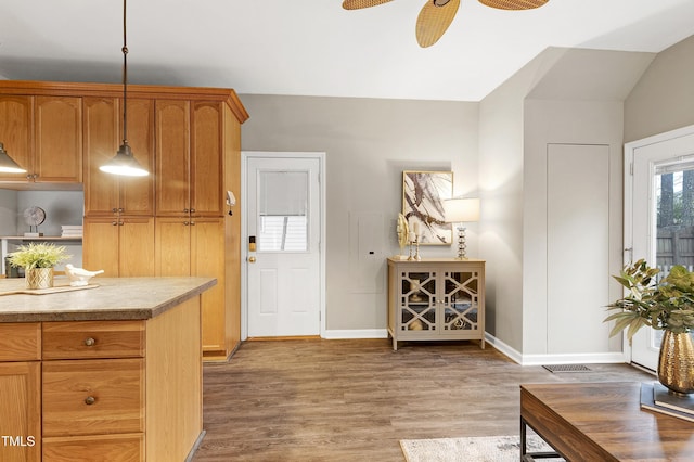 kitchen featuring ceiling fan, wood finished floors, baseboards, light countertops, and hanging light fixtures