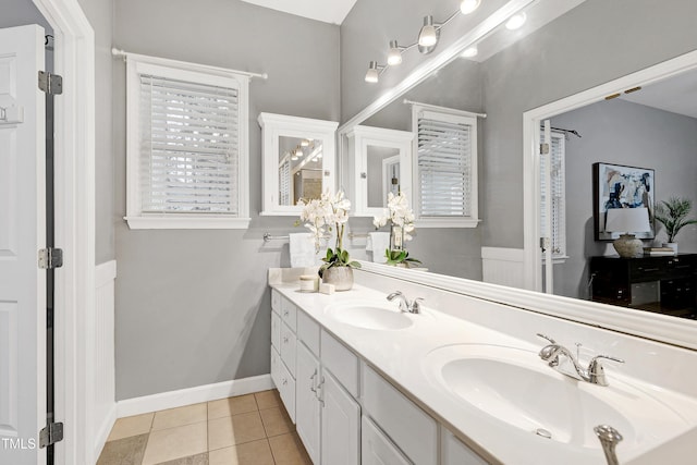 full bathroom featuring double vanity, baseboards, a sink, and tile patterned floors