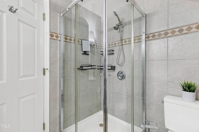 full bath featuring a stall shower and toilet