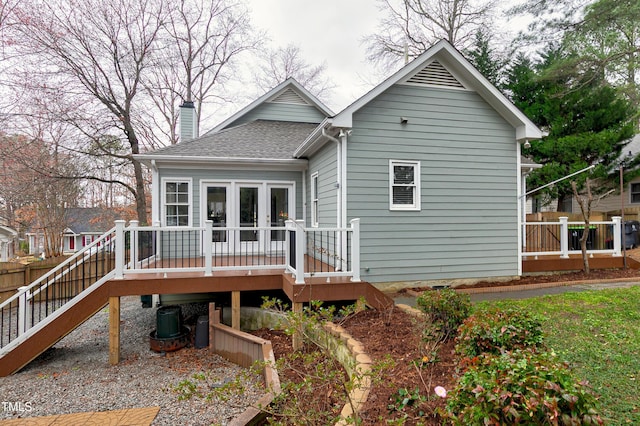 rear view of house with a chimney, roof with shingles, fence, cooling unit, and a wooden deck