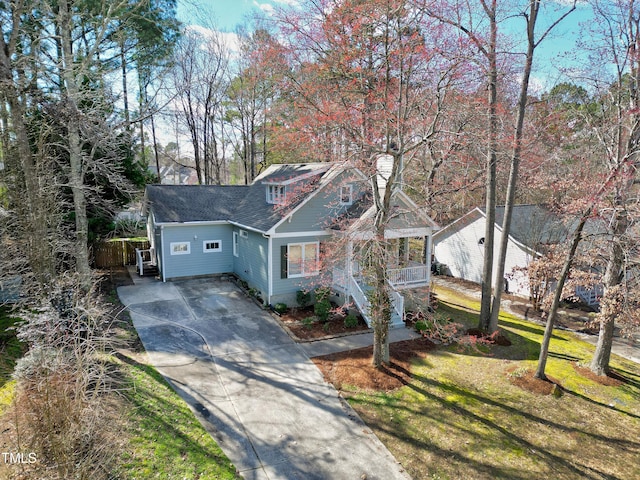 view of front of property with driveway, a porch, a front lawn, and a shingled roof