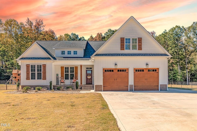 modern inspired farmhouse featuring a yard, concrete driveway, covered porch, and fence