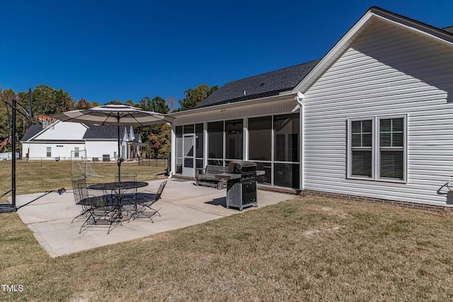 back of property with a sunroom, a patio, and a lawn