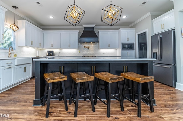 kitchen featuring visible vents, custom exhaust hood, black microwave, stainless steel refrigerator with ice dispenser, and a sink