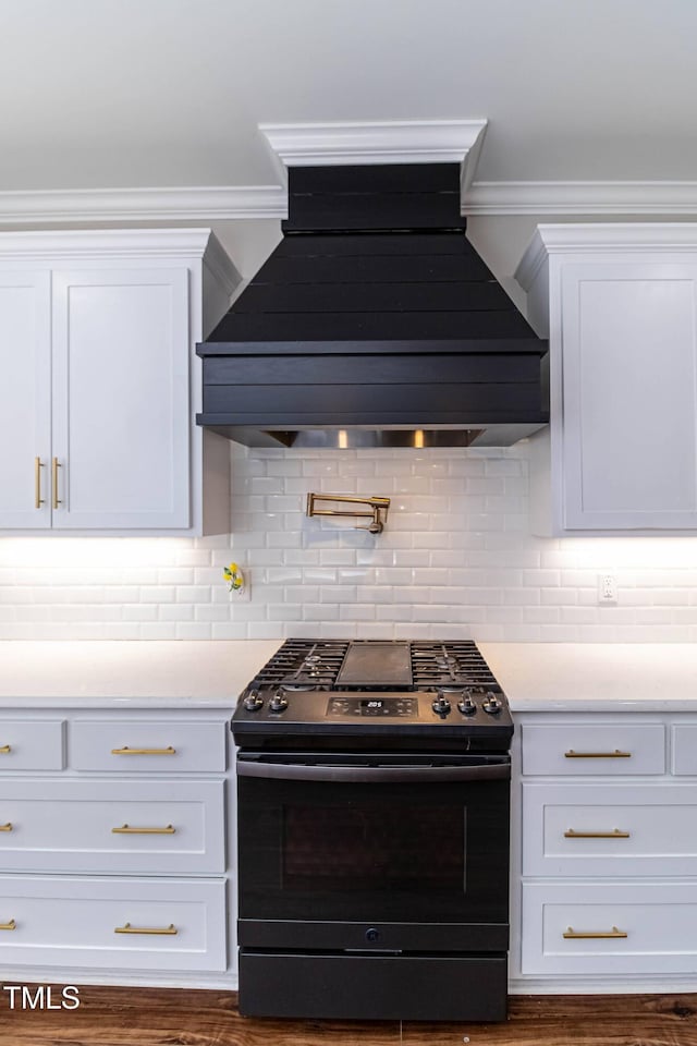 kitchen with white cabinets, light countertops, gas range, and custom range hood