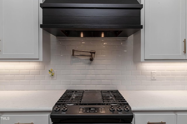 kitchen with range hood, light stone counters, backsplash, and black gas range oven