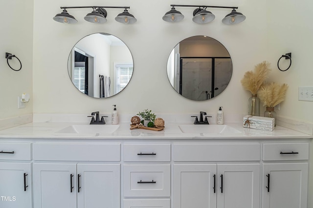 bathroom featuring an enclosed shower, a sink, and double vanity