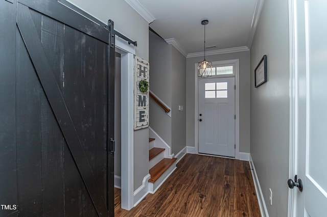 foyer featuring a barn door, baseboards, ornamental molding, stairway, and dark wood finished floors