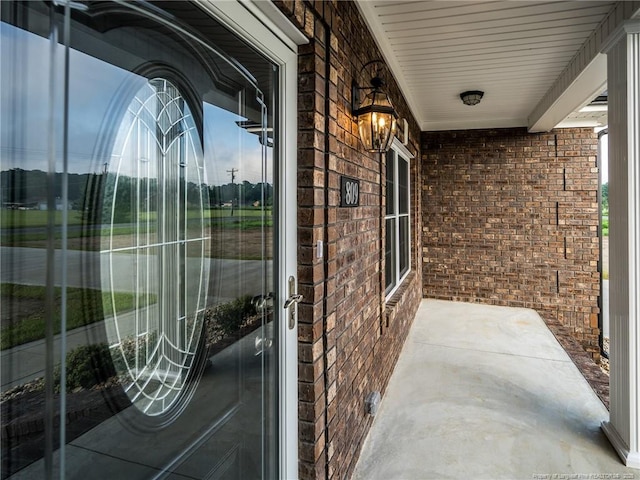 doorway to property with brick siding and a porch