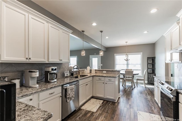 kitchen featuring stainless steel appliances, backsplash, dark wood-type flooring, a sink, and a peninsula