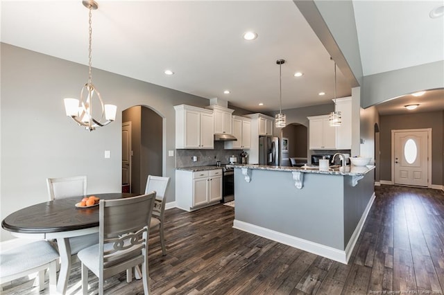 kitchen with stainless steel appliances, arched walkways, and a peninsula