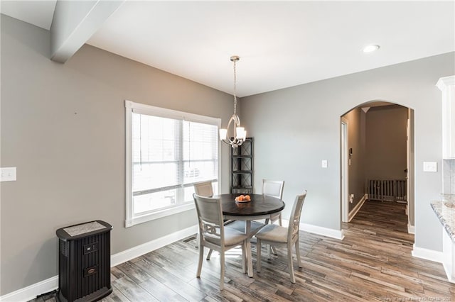 dining space featuring baseboards, arched walkways, and wood finished floors