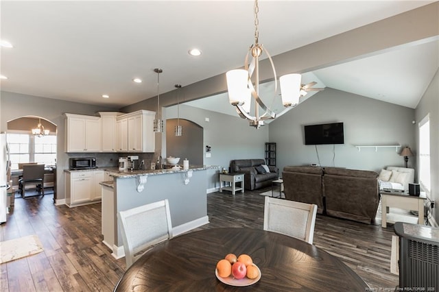 dining room with arched walkways, a chandelier, lofted ceiling, recessed lighting, and dark wood-style flooring